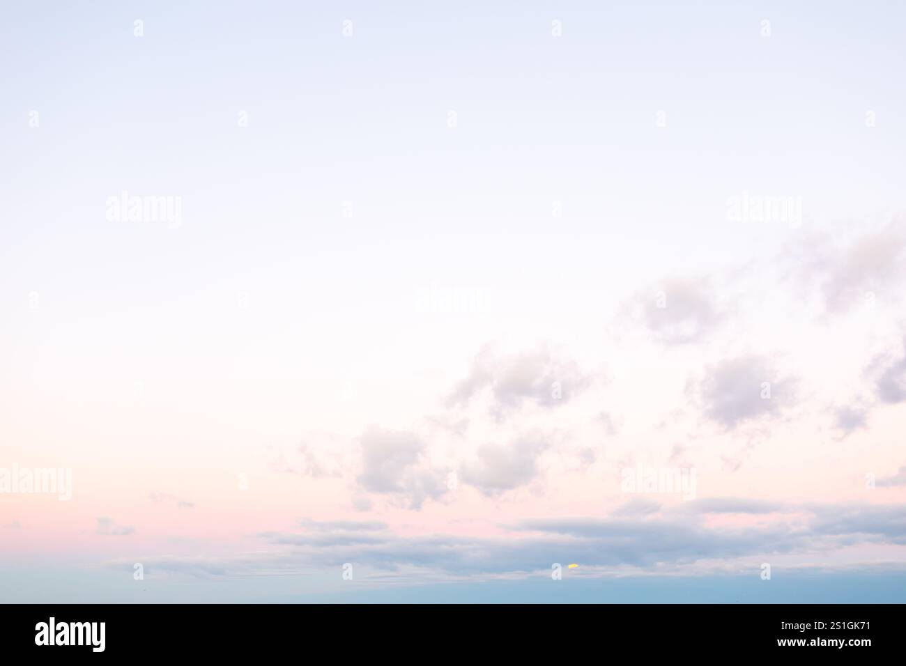 Soft pastel sky at dawn over the horizon with gentle clouds and a hint ...