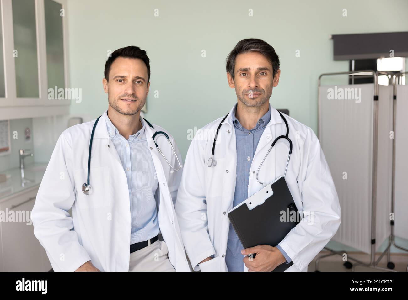 Two confident male doctor colleagues with stethoscopes posing together Stock Photo
