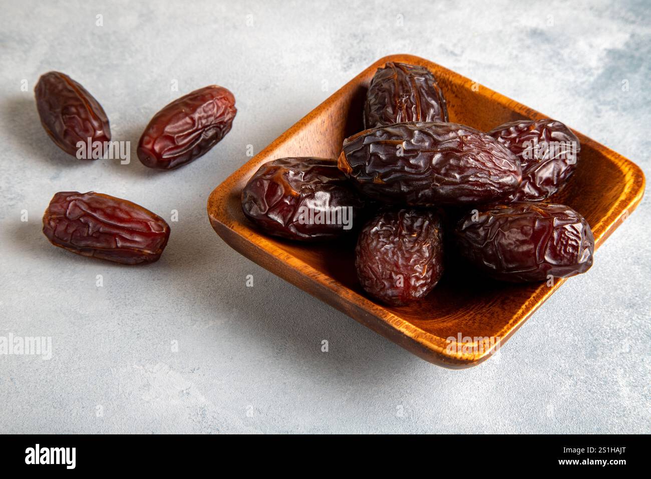 Large dates fruit in a wooden bowl on bright background Stock Photo