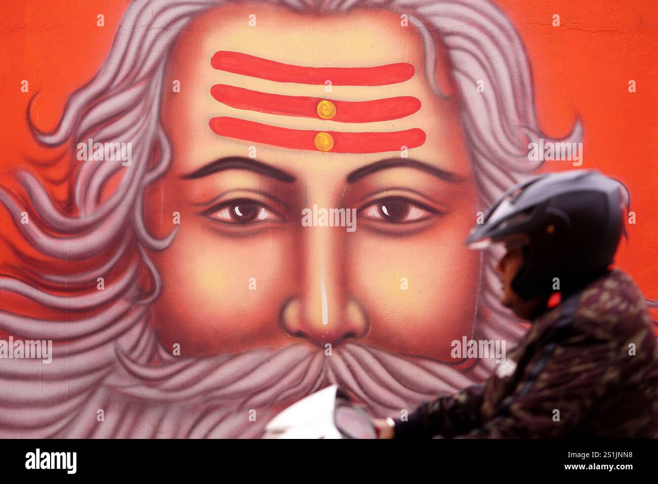 Indian People walks past a wall mural, ahead of the Maha Kumbh Mela