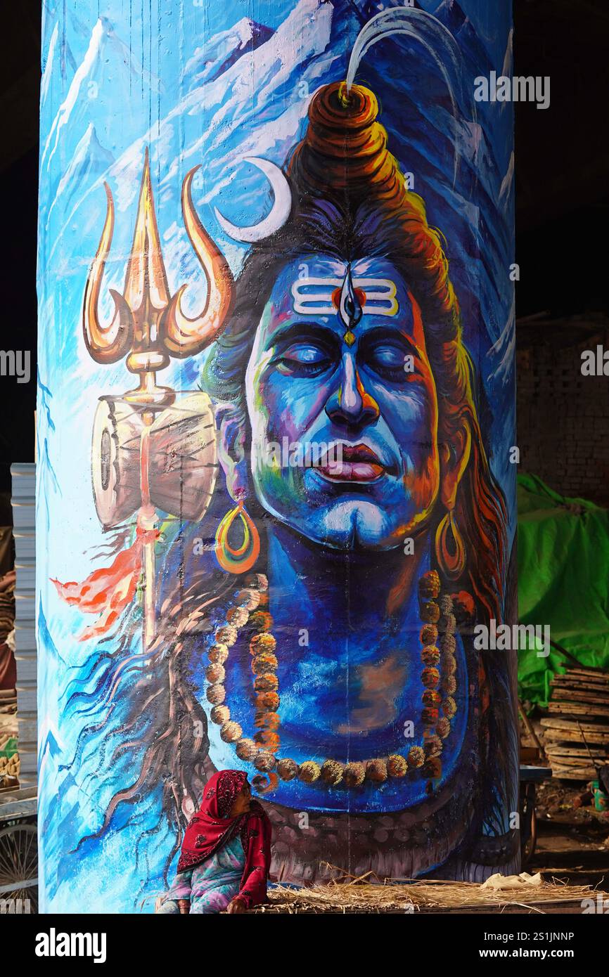 Indian People walks past a wall mural, ahead of the Maha Kumbh Mela