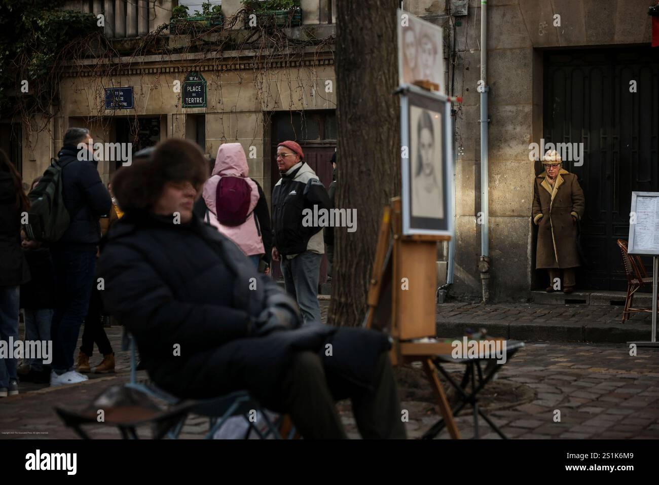 A man waits in the sun next to the artists of Montmartre in Paris