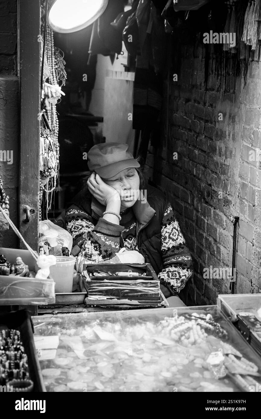 asian woman in small "hole in the wall " store asleep in Chinatown new york city usa Stock Photo