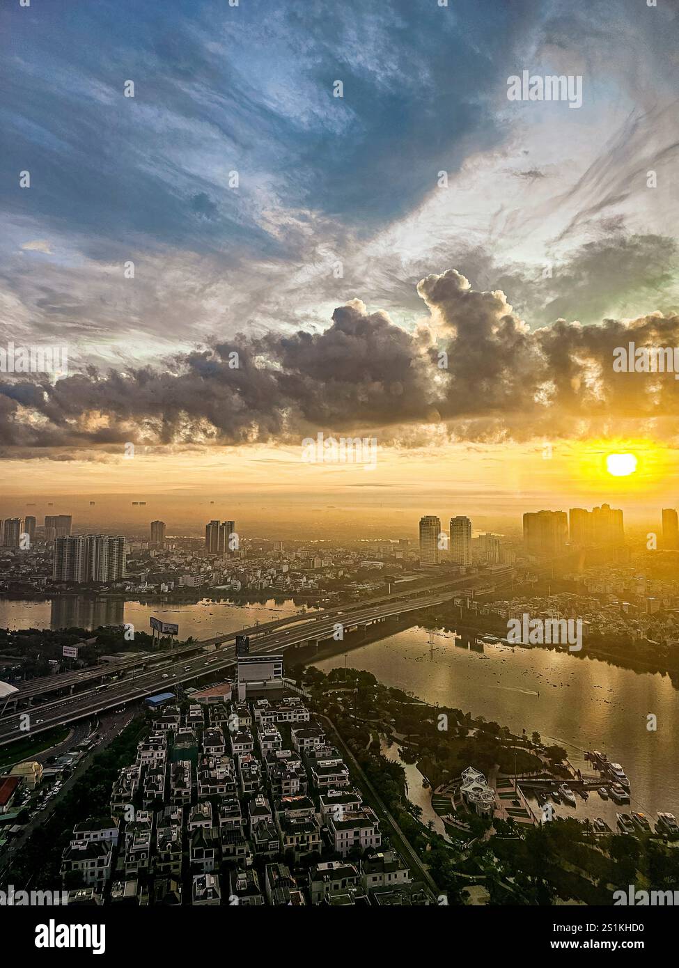 A city skyline with a bridge and a river. The sun is setting and the ...