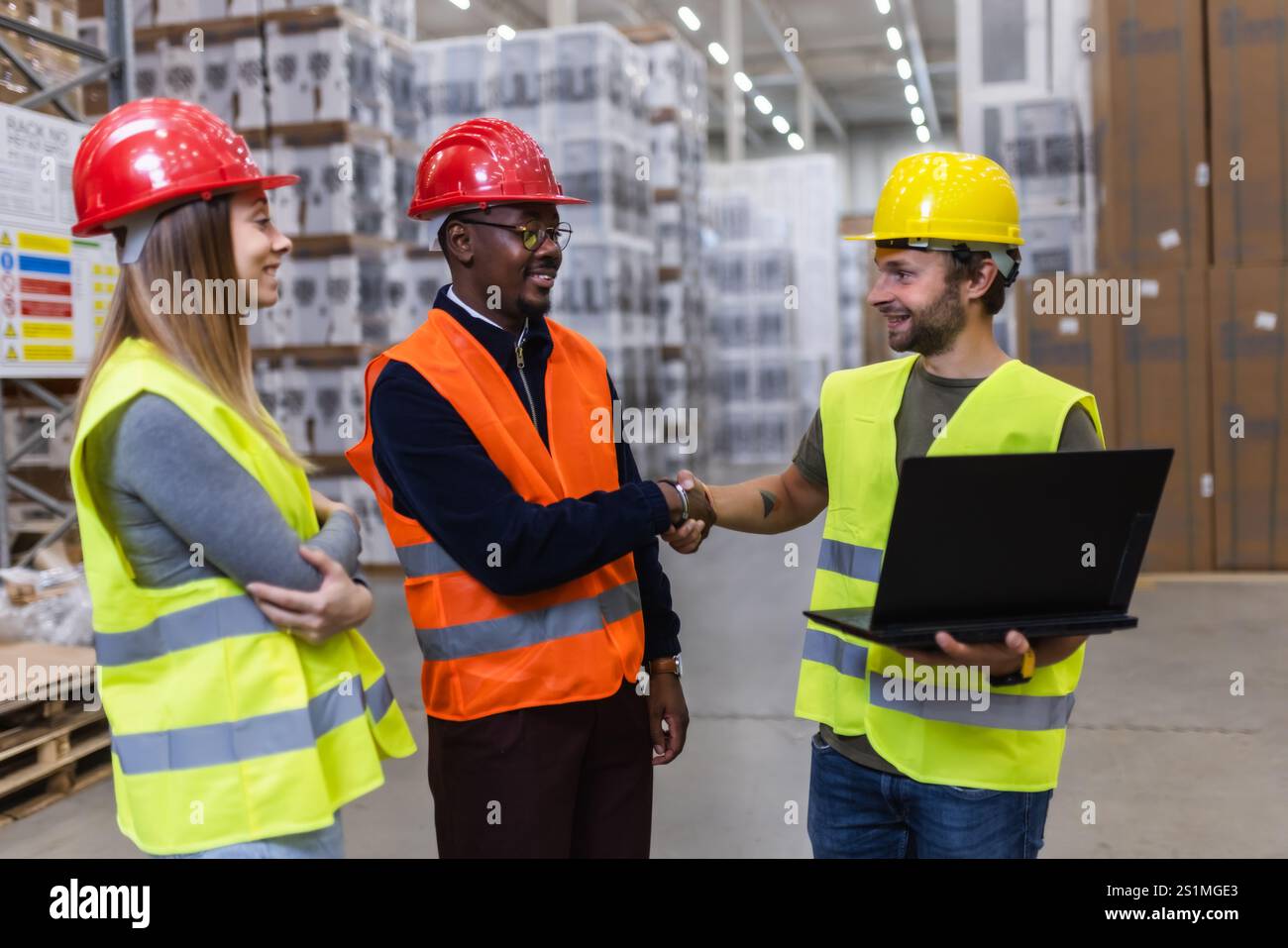 Three construction workers wearing safety gear collaborate in a busy ...