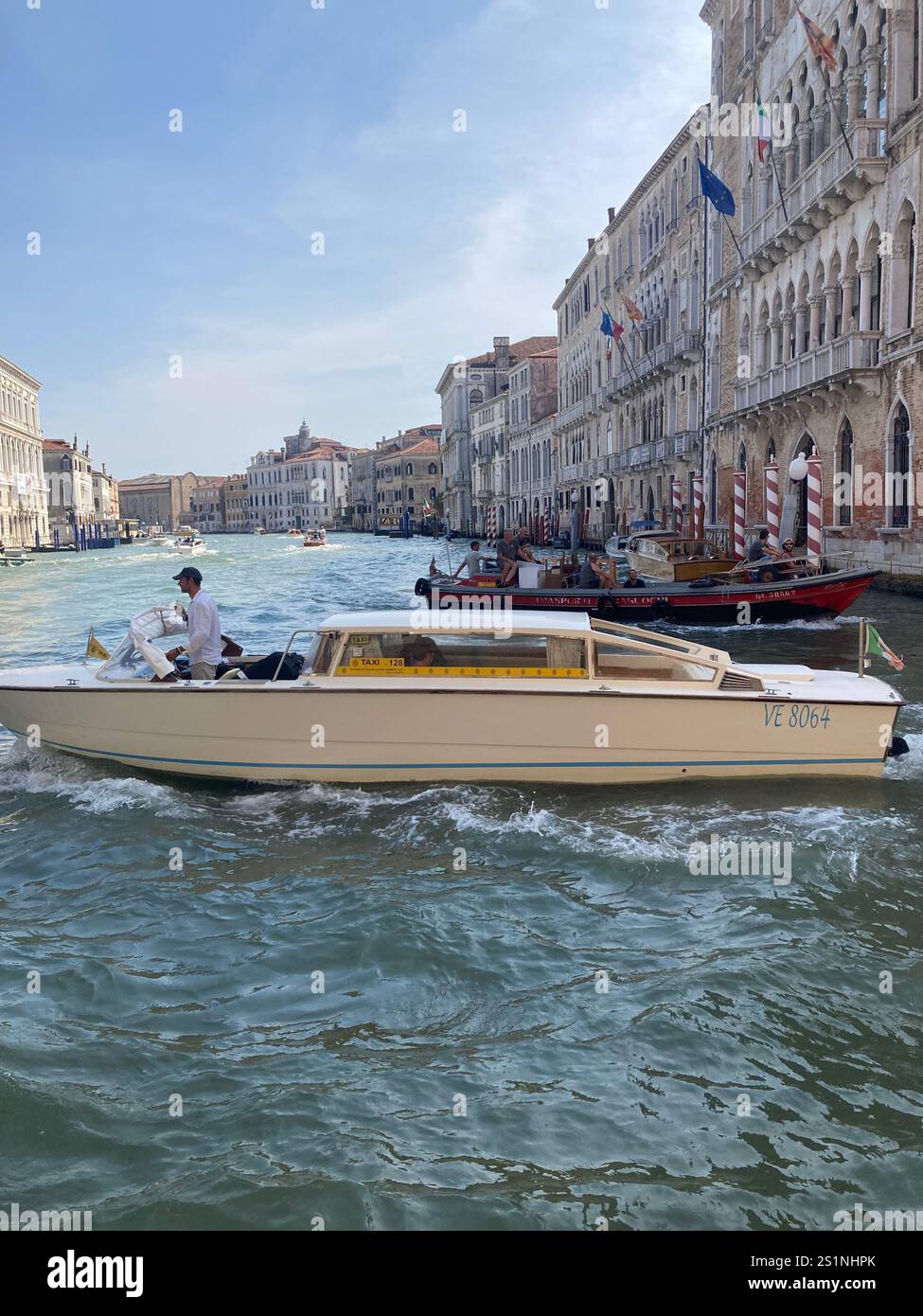 A motor cruiser on the Grand Canal, Venice, under a blue sky - Smartphone Captured Stock Image