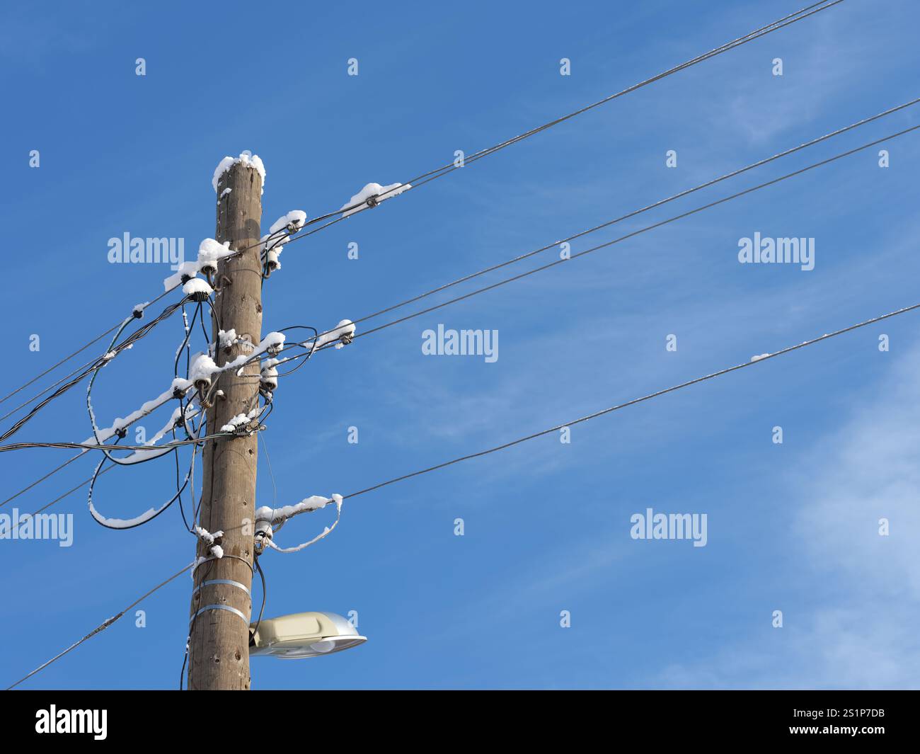 An old electric wooden pole with a lamp and electricity cables hanging ...