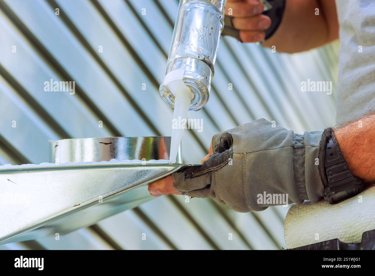 Construction worker uses caulking gun to apply sealant to ventilation ...
