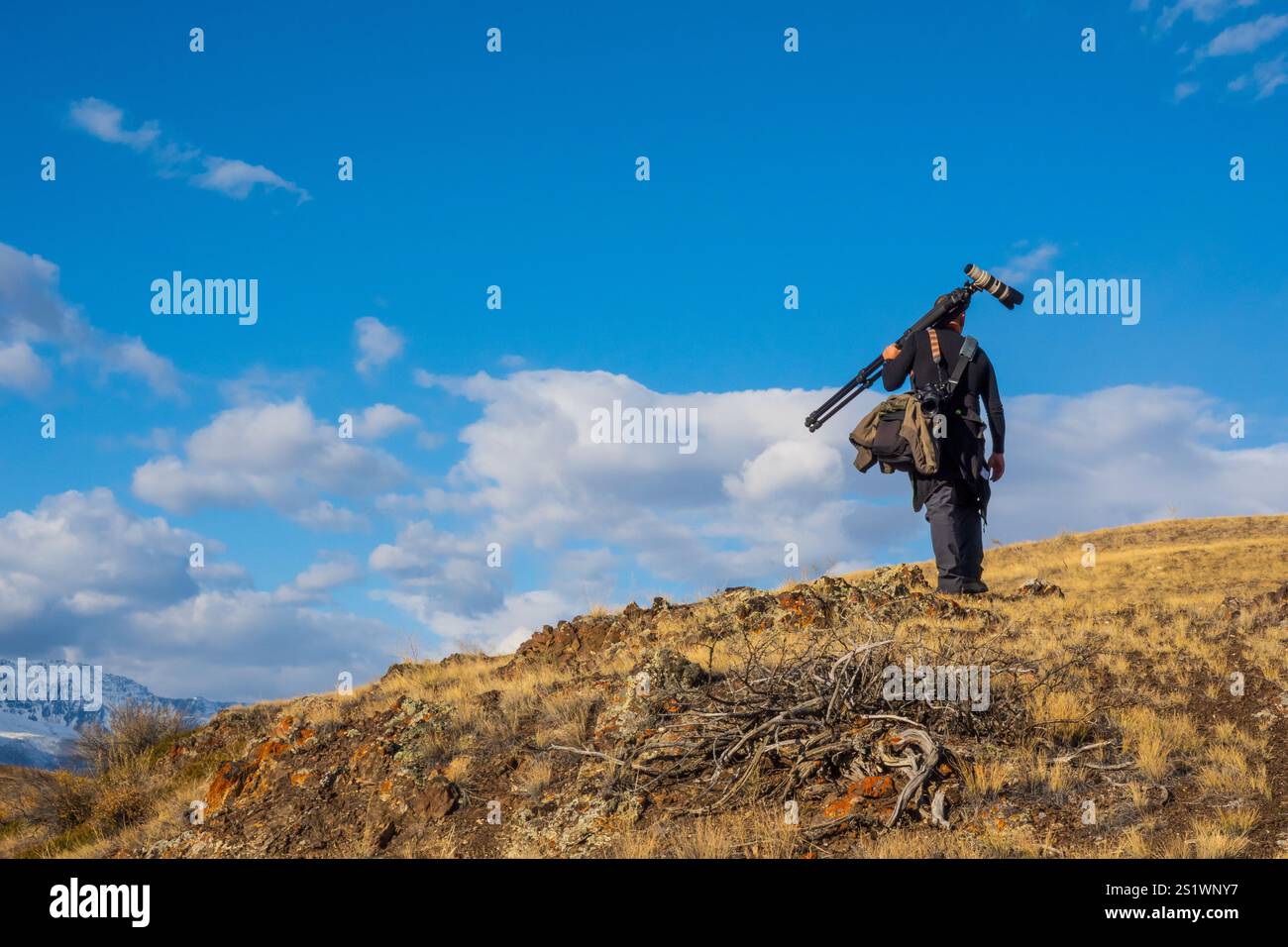 Outdoor photographer explores a rugged landscape with camera and tripod ...