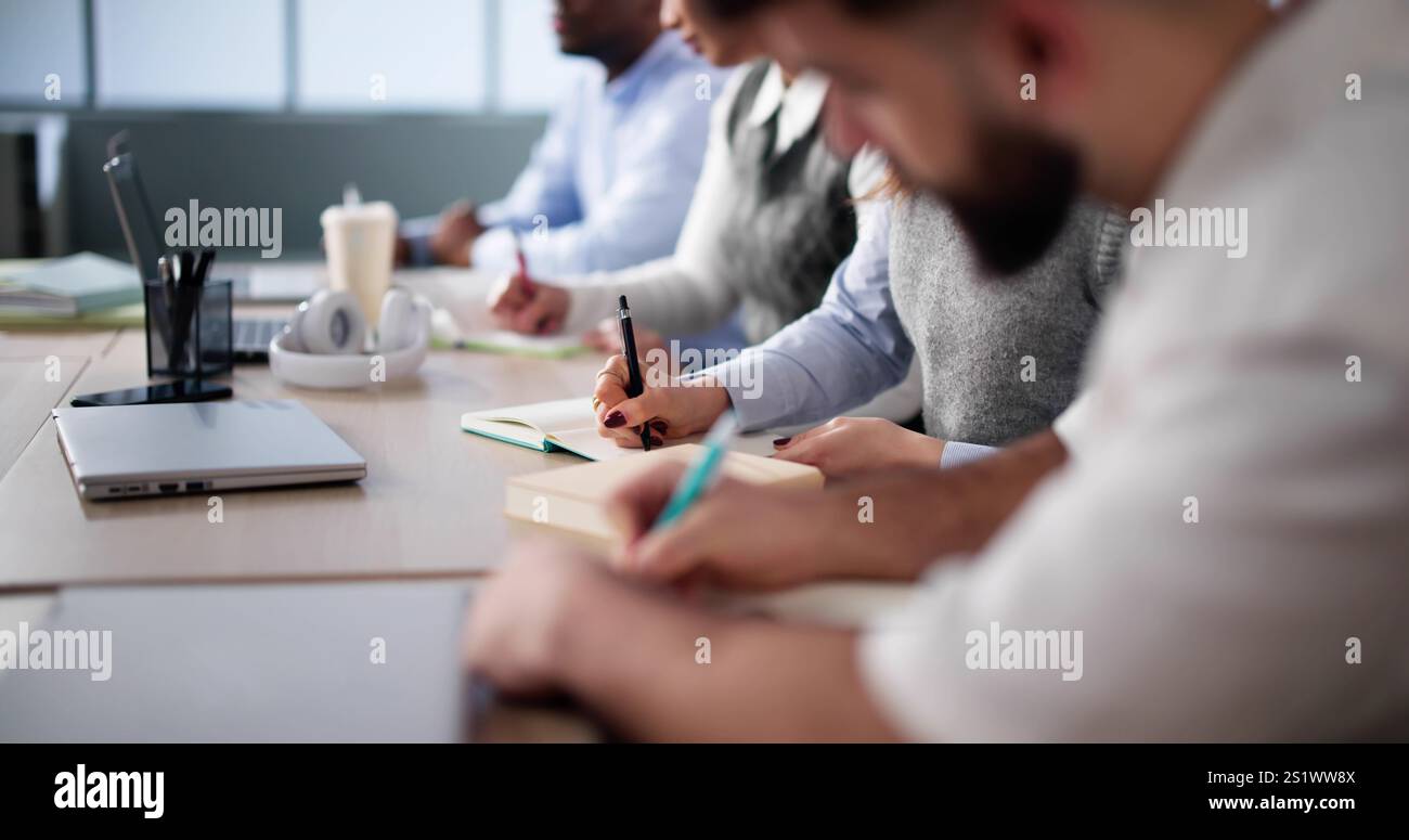 Studying In Classroom At Campus. Students Writing In Class Stock Photo