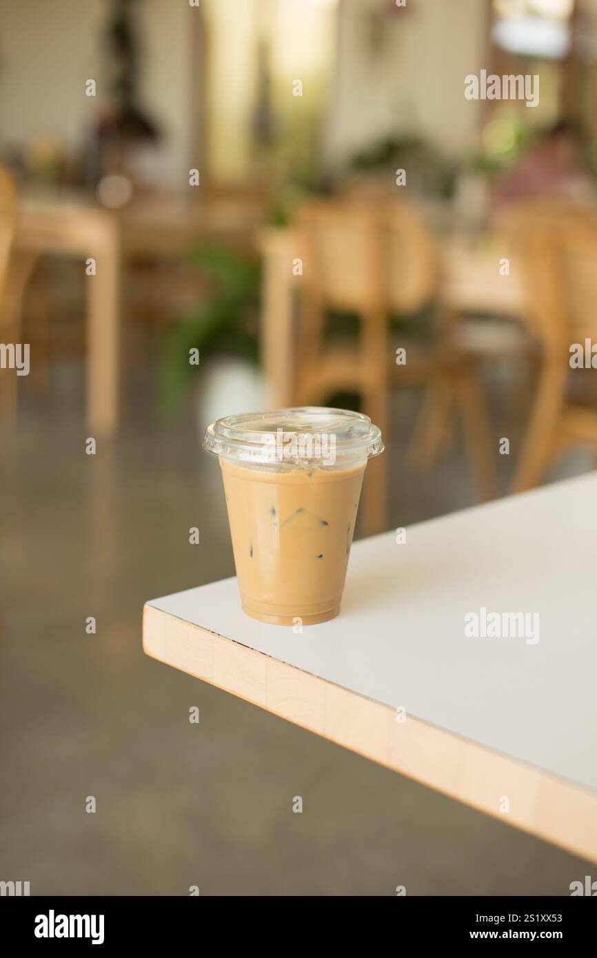A refreshing iced coffee sits on a table in a cozy caf��; the perfect drink to enjoy while relaxing in a warm and inviting atmosphere, ideal for summer Stock Photo