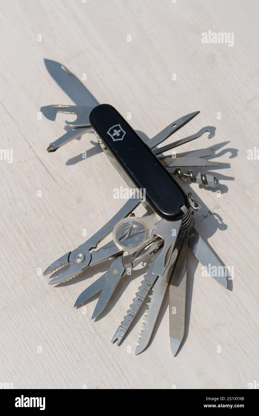 Swiss Army knife with a black handle and silver blades. The knife has a variety of tools, including a screwdriver, scissors, and a can opener Stock Photo