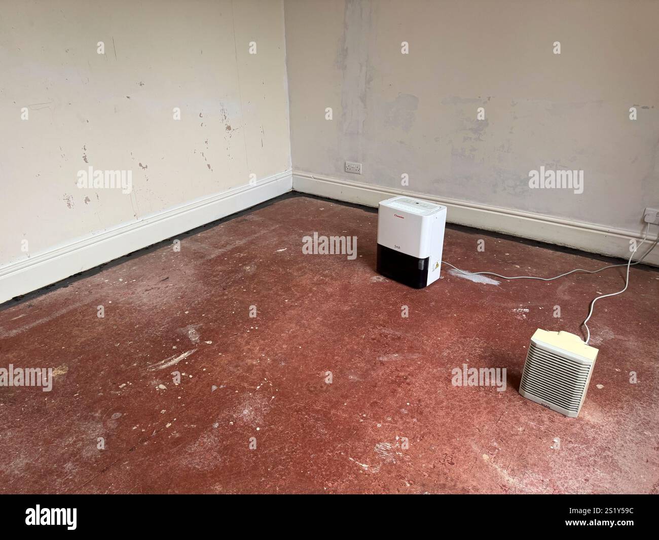 Dehumidifier and electric fan heater to dry out damp floor in a house in England - Smartphone Captured Stock Image