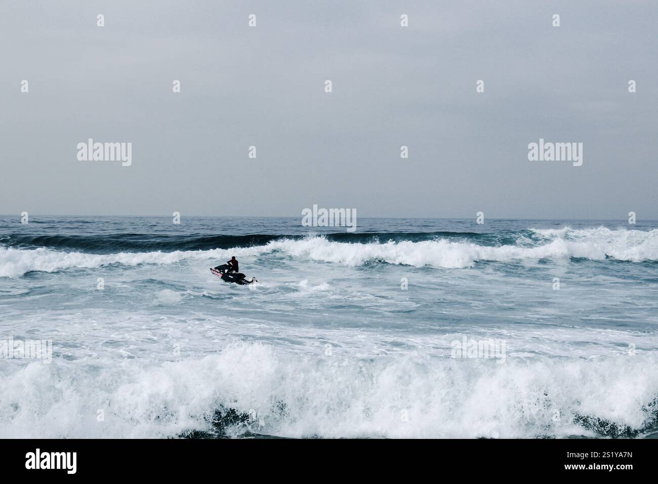 Beim tow-in wird ein Surfer mit Hilfe von einem Jet-Ski und einer tow-Leine in eine große, sich brechende Wasserwelle gezogen, Nazaré Portugal. Stock Photo