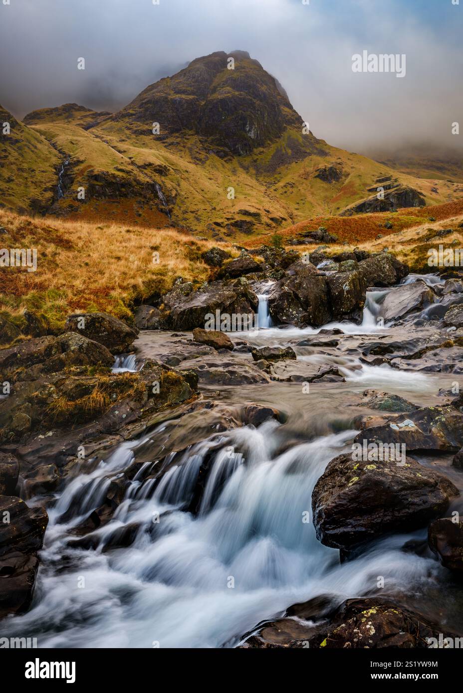 Deepdale beck cascading down the mountainside into Deepdale valley, looking towards Fairfield which is obscured by cloud & hill fog. Stock Photo