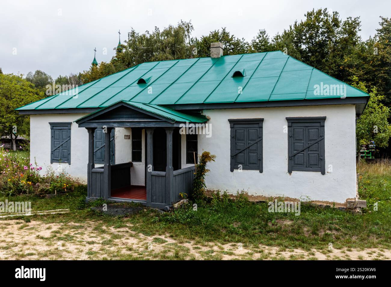 A small house with a green roof and white walls. The house is ...