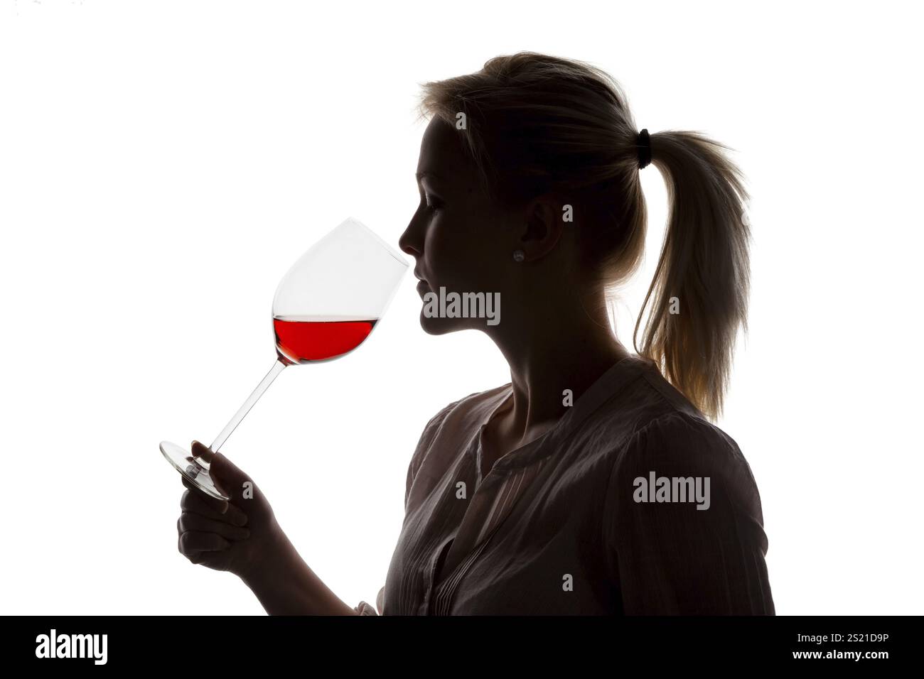A young woman at a wine tasting. Tasting a glass of red wine in a red wine glass Stock Photo