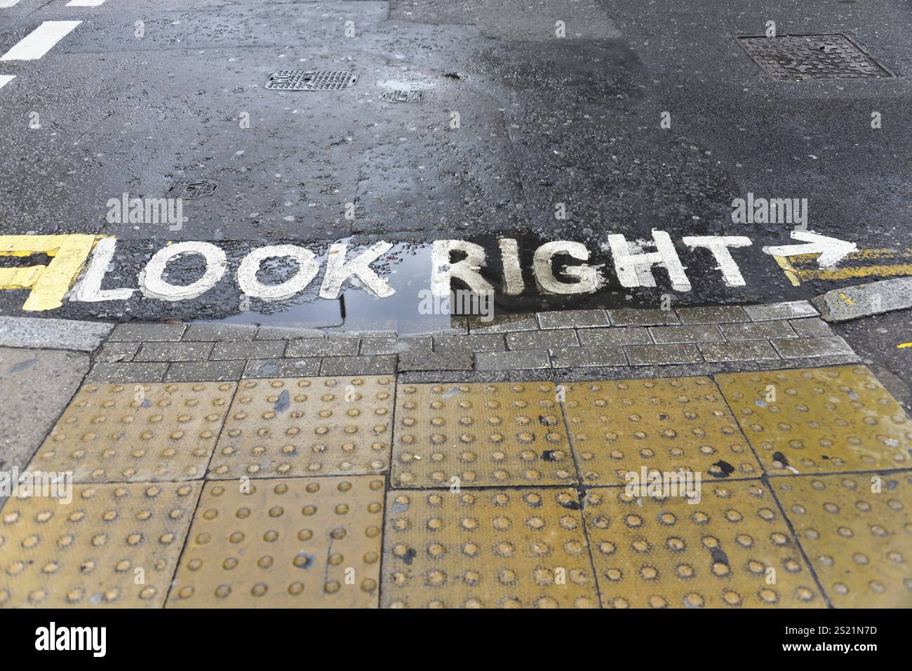 Yellow traffic sign on wet pavement with 'LOOK RIGHT' sign, London, London region, England, United Kingdom, Europe Stock Photo