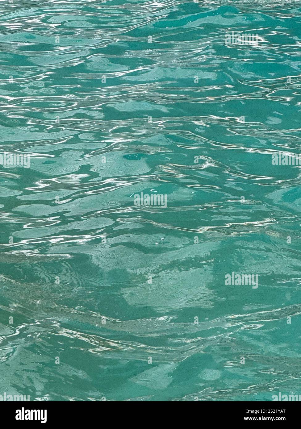 This image captures the mesmerizing texture and vibrant hues of turquoise water in a serene setting. The rippling surface reflects sunlight. - Smartphone Captured Stock Image