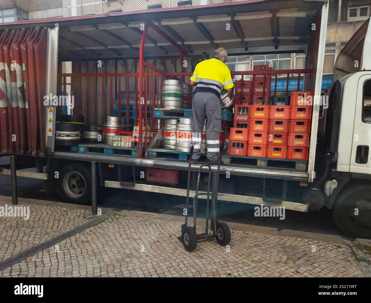 Man working on supply truck with beer and coke bottles and kegs, drinks delivery lorry for restaurants and bars - Smartphone Captured Stock Image