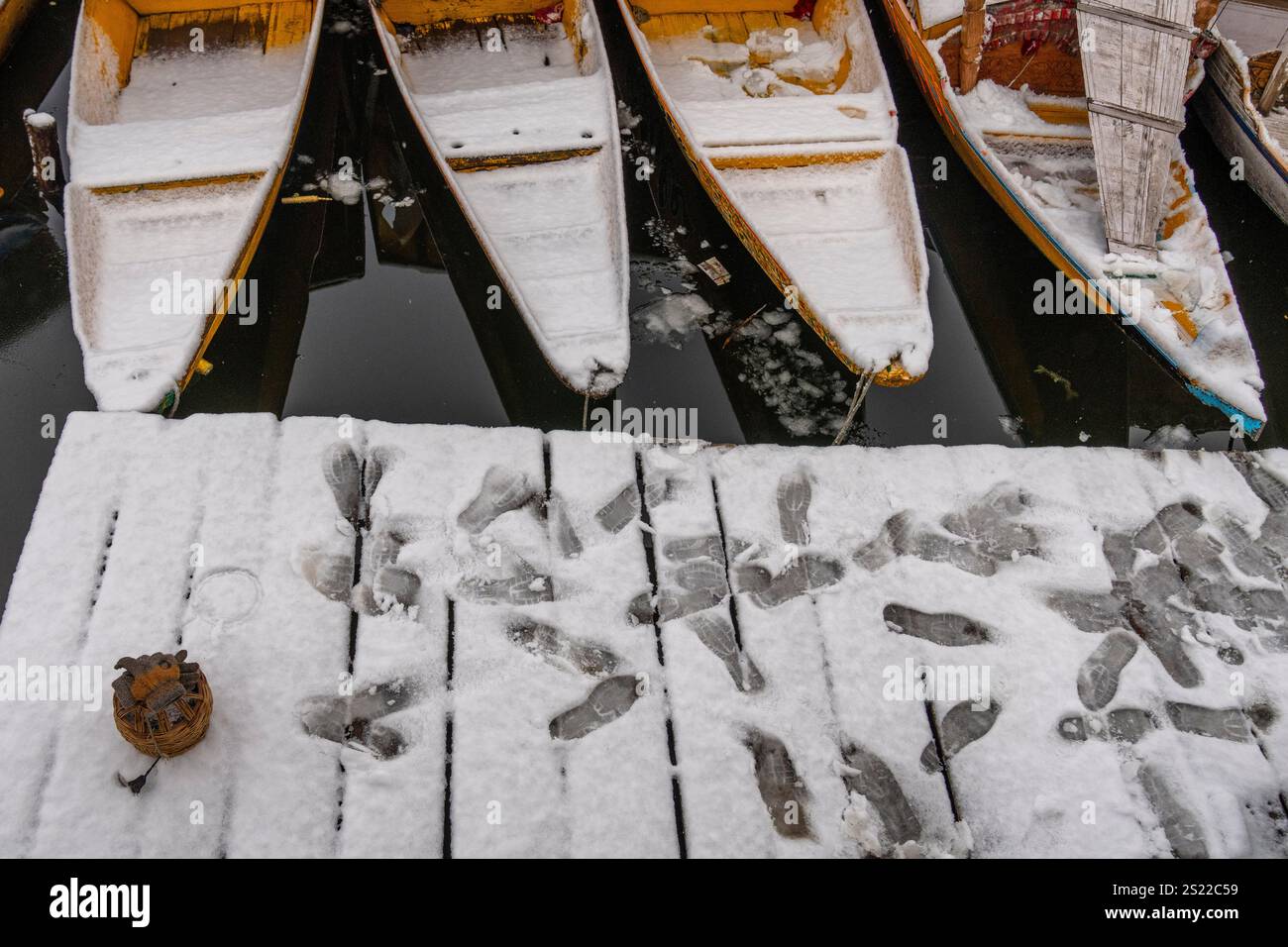 Footprints are left in the snow on a jetty near anchored boats on the
