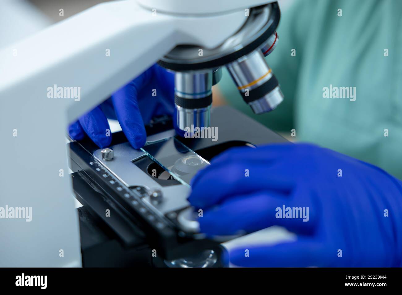 Unrecognizable female doctor in clinic focused on scientific study using microscope Stock Photo