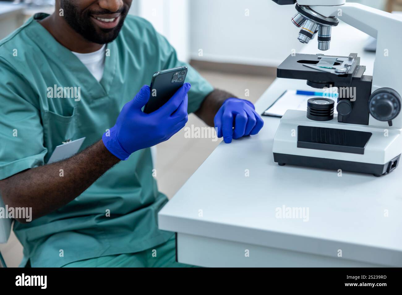 Scientist in laboratory conducting experiment and tests on samples using mobile phone and microscope Stock Photo