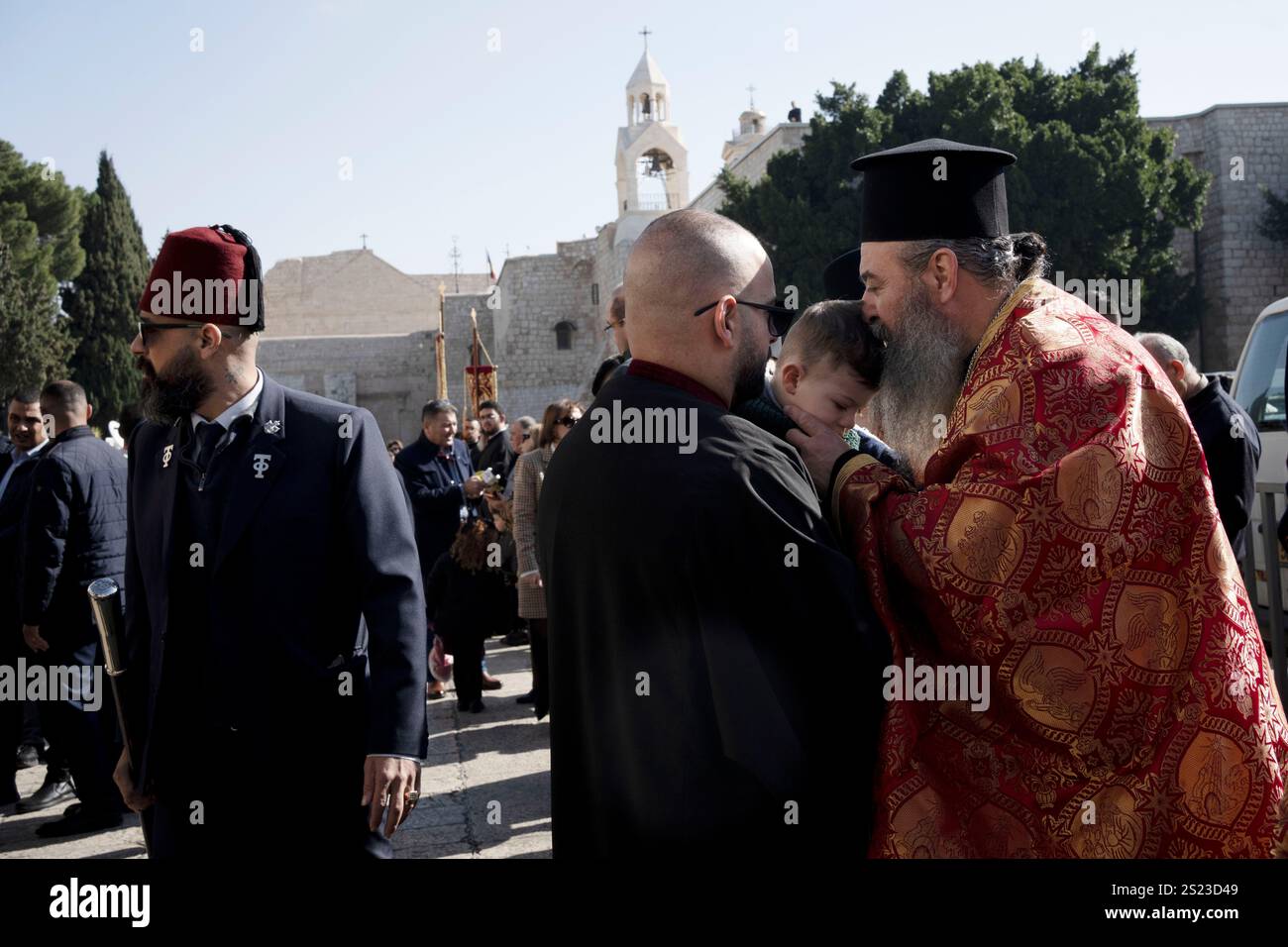 A Greek Orthodox clergy member kisses a young worshipper at the Church