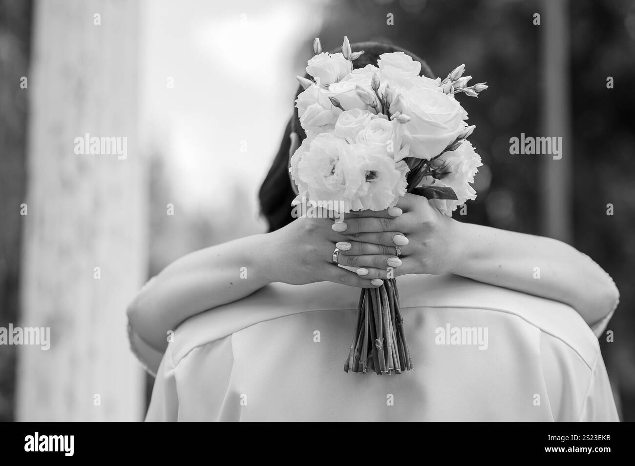 Romantic Black and White Wedding Embrace with Floral Bouquet. Stock Photo