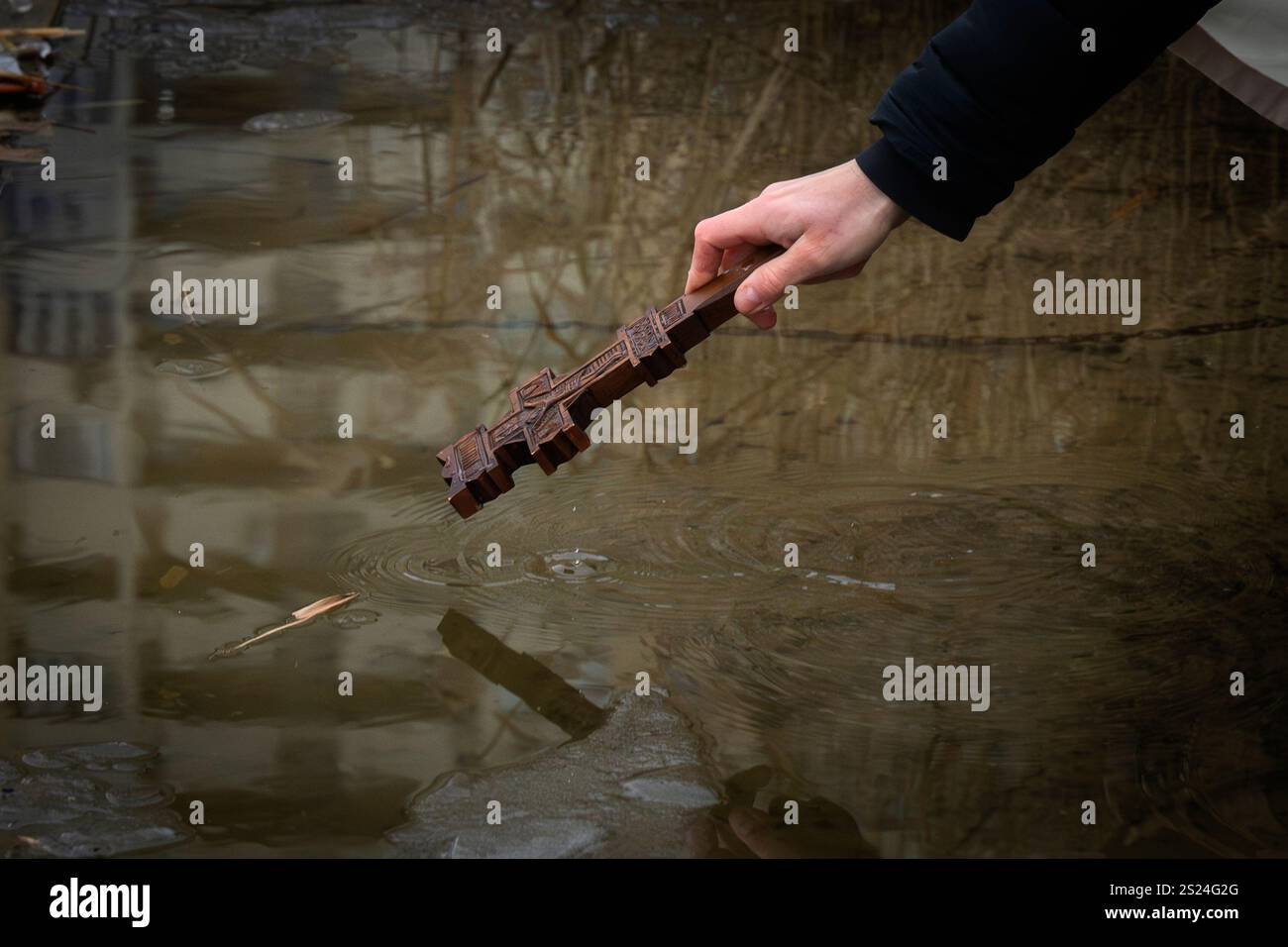 A Greek Catholic priest dips the cross into the Jordan Lake to bless
