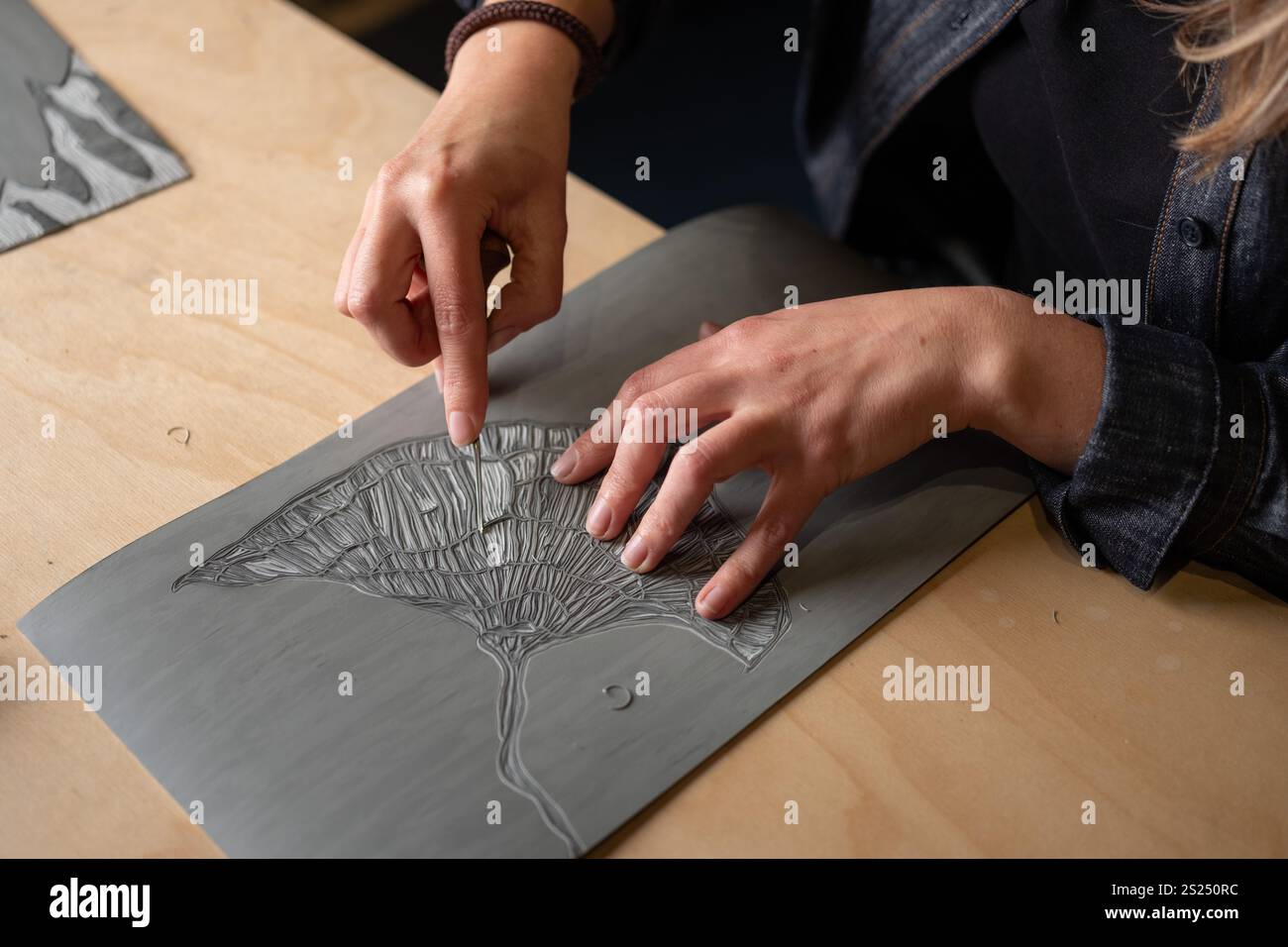 An artist carving a woodcut design for printing. Stock Photo