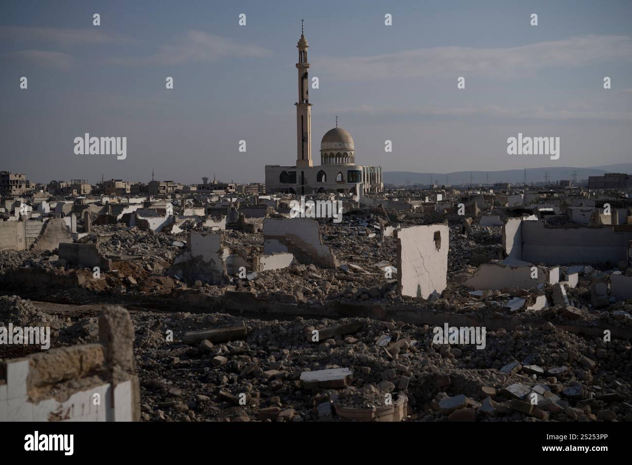 A heavily damaged mosque stands next to buildings that were completely ...