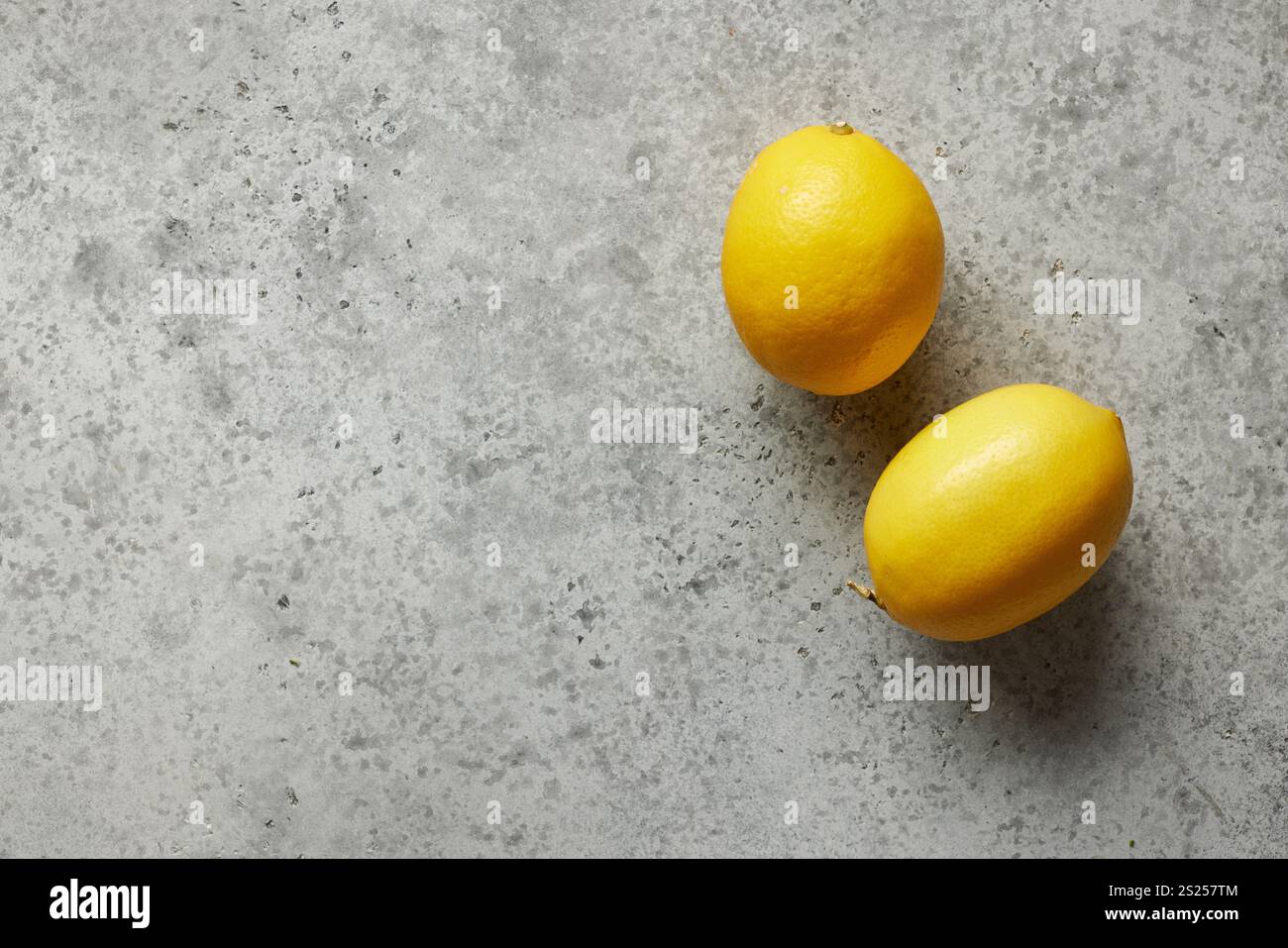 two fresh lemons on grey kitchen table background, top view Stock Photo