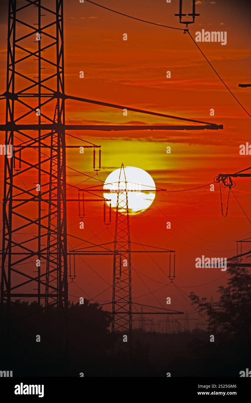 Power transmission towers silhouetted against a sunset sky Stock Photo ...