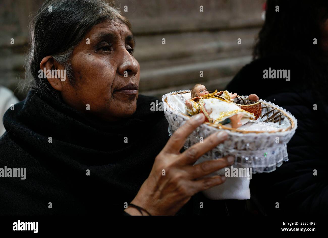 A woman holds a statue of baby Jesus during Epiphany Mass at a Catholic