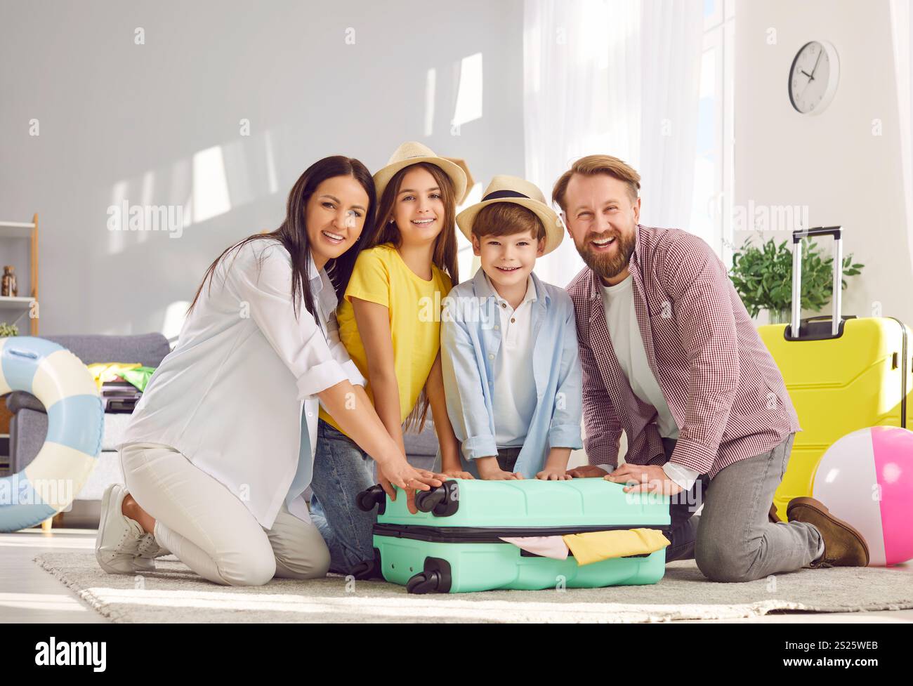Portrait of happy family with children packing bag for summer vacation trip. Stock Photo