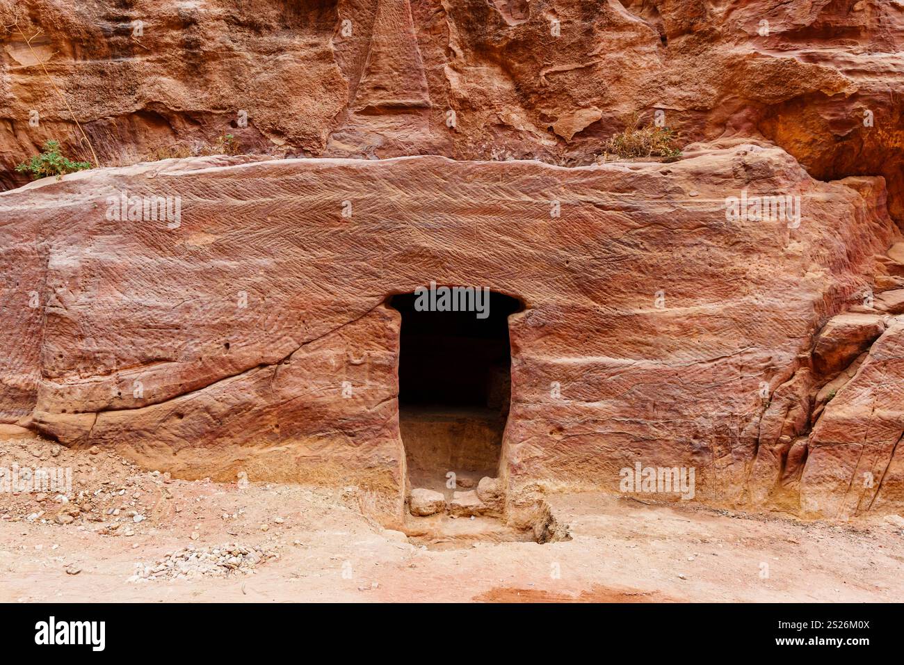 A carved opening set into the red sandstone cliff, showcasing ancient ...