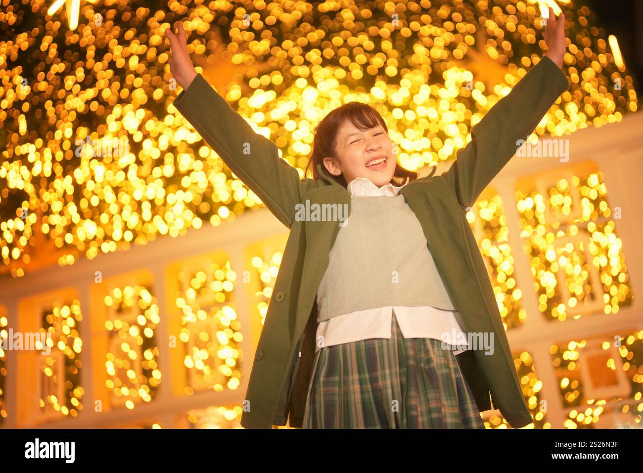 A cheerful child stands with arms raised in a joyful expression as she ...