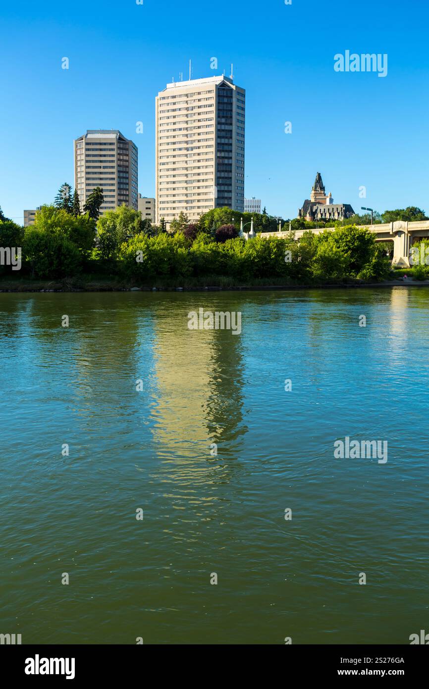 A city skyline with a large building in the background and a bridge in the foreground. The water is calm and reflects the buildings and bridge Stock Photo