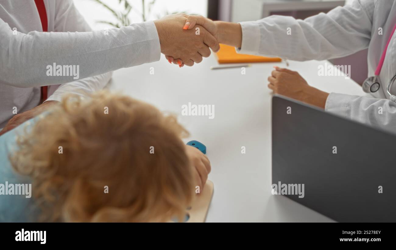 Trusting A Doctor Doctor shaking hands with father while son plays in the clinic room ...
