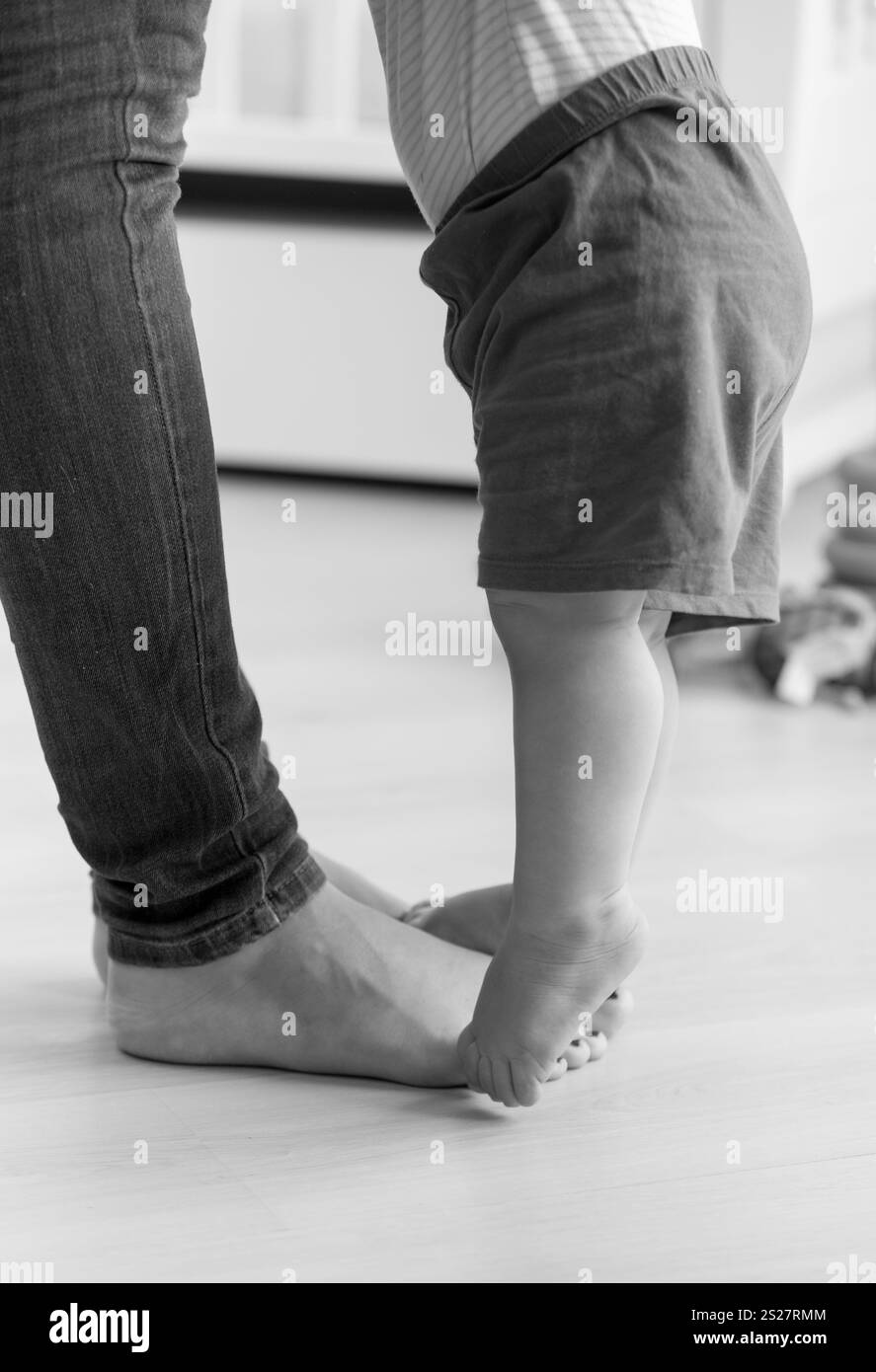 Closeup black and white image of baby boy walking to his mother at living room Stock Photo