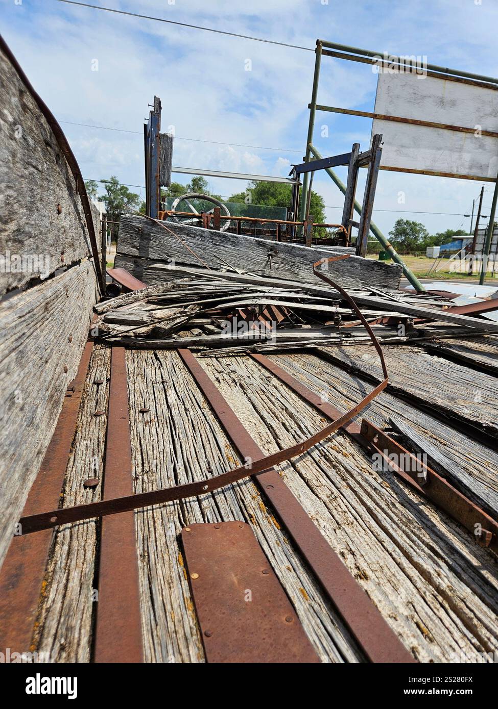 Old wooden wagon with rusty metal and weathered wood in an abandoned area under a blue sky - Smartphone Captured Stock Image