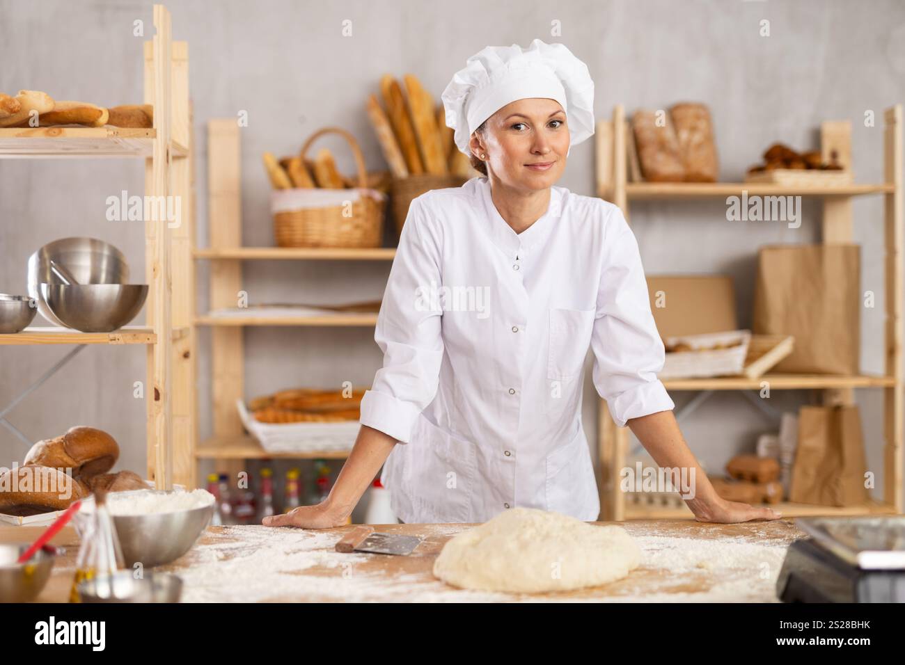 Portrait of successful young woman baker in apron smiling at camera ...