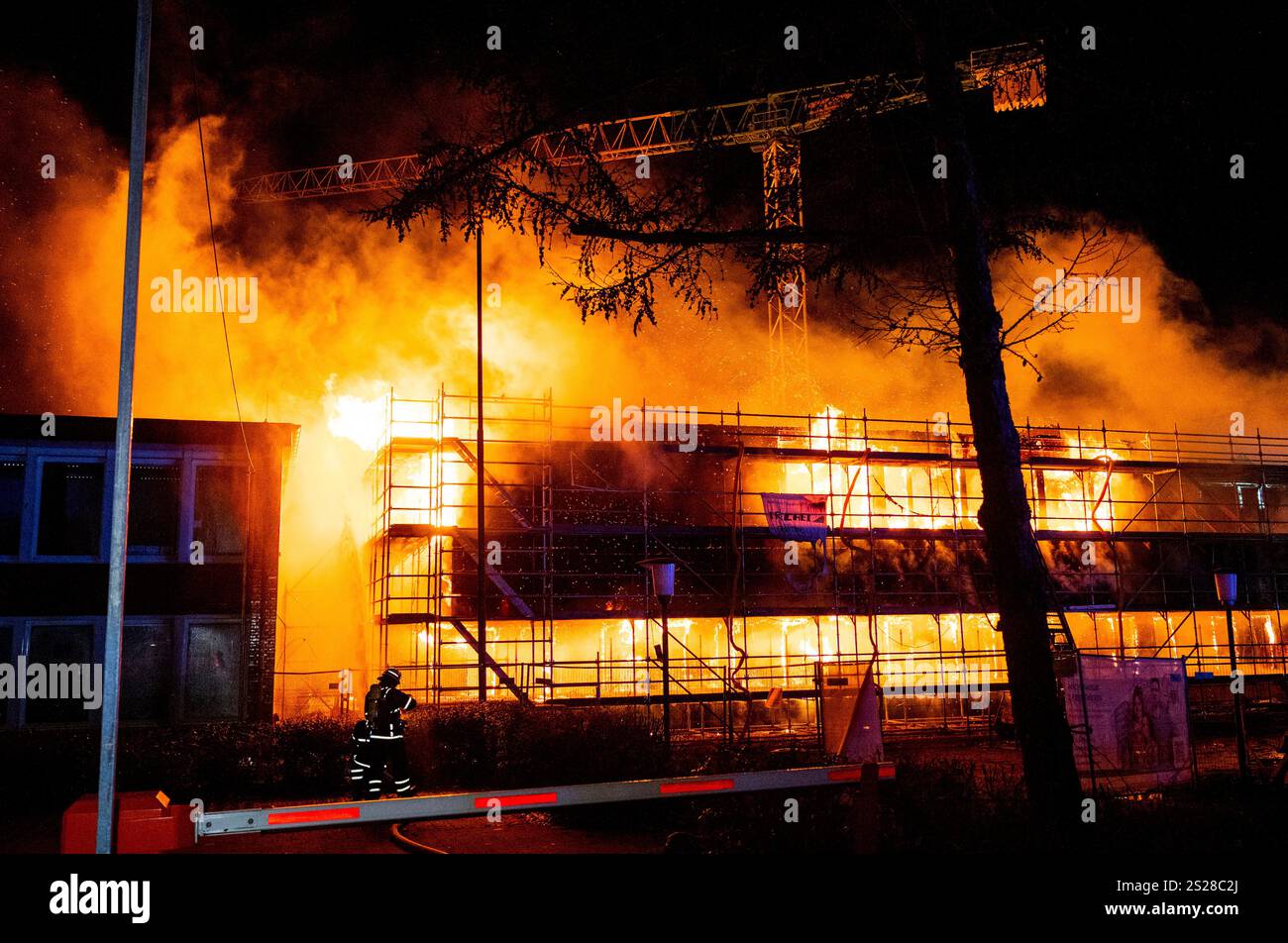 Firefighters extinguish a burning new school building in the Lohbrügge