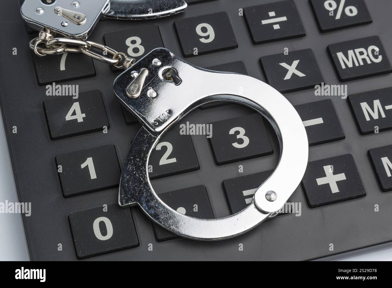 Calculator and handcuffs on a white background. Symbol photo for white ...