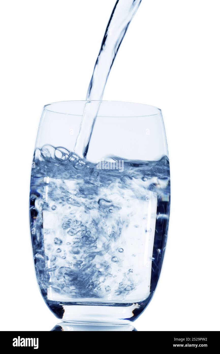 Water is poured into a glass, symbolising drinking water, freshness, demand and consumption Stock Photo