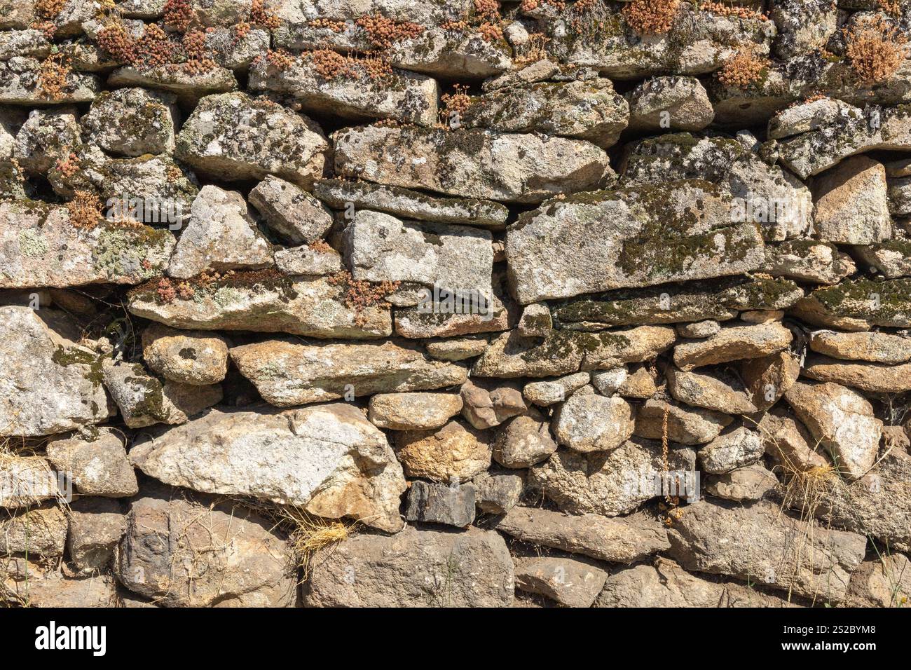 Detail of a granite wall with moss, large and small gray stones stacked ...