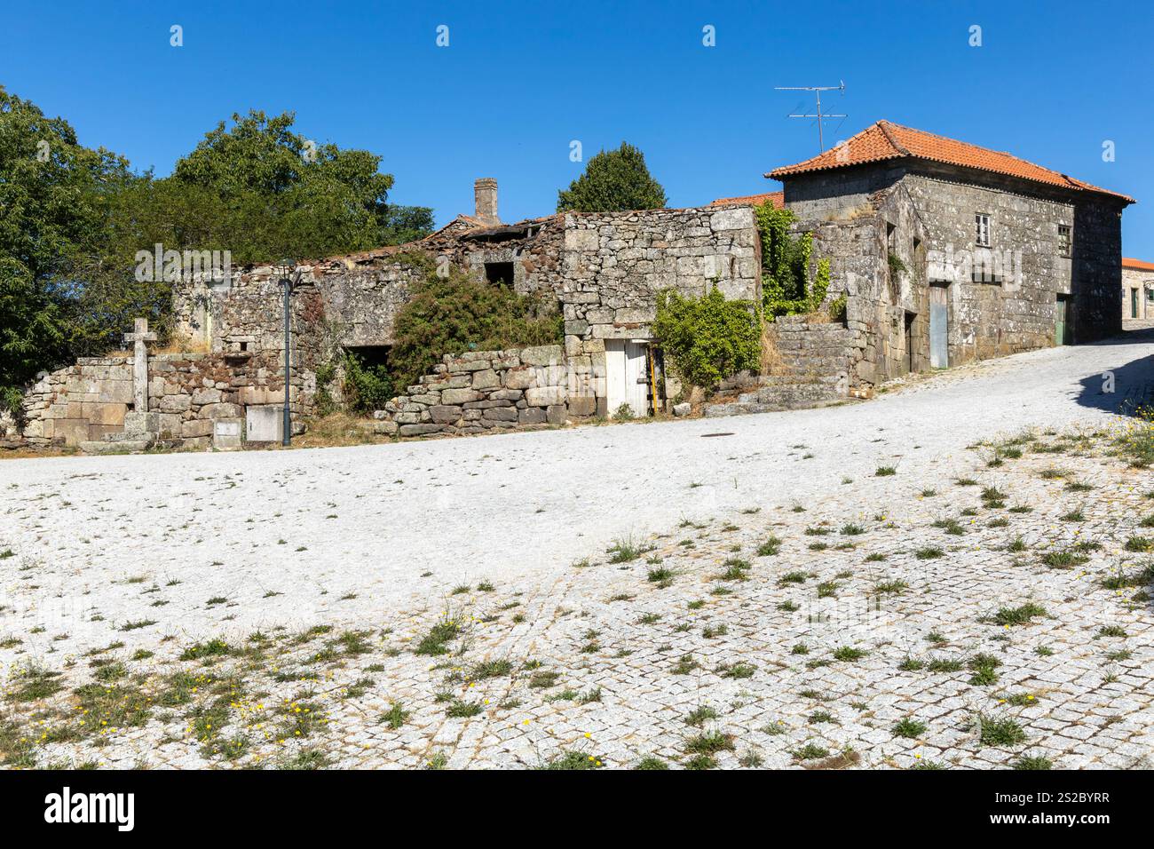Old abandoned granite Portuguese house with religious christianity cross and blue sky Stock Photo