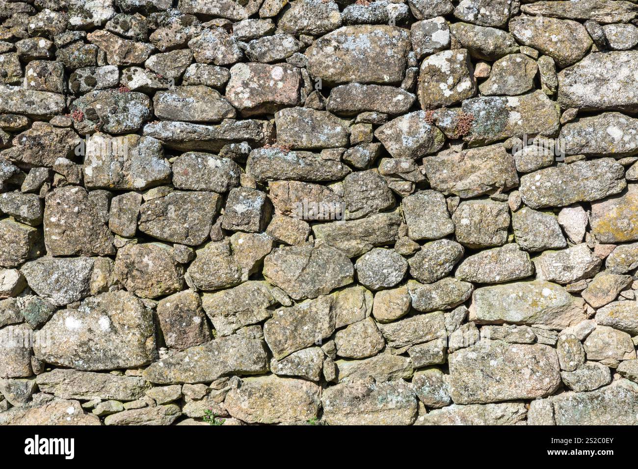 Detail of a granite wall with moss, large and small gray stones stacked ...