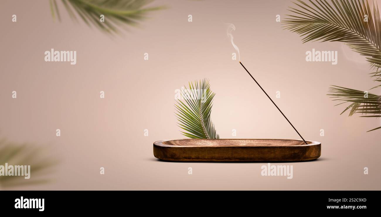Burning incense stick in a wooden holder with palm leaves decoration Stock Photo